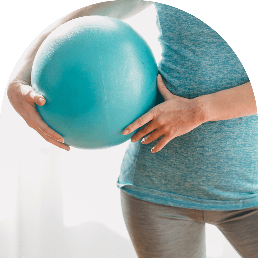 woman holding pilates ball next to hip