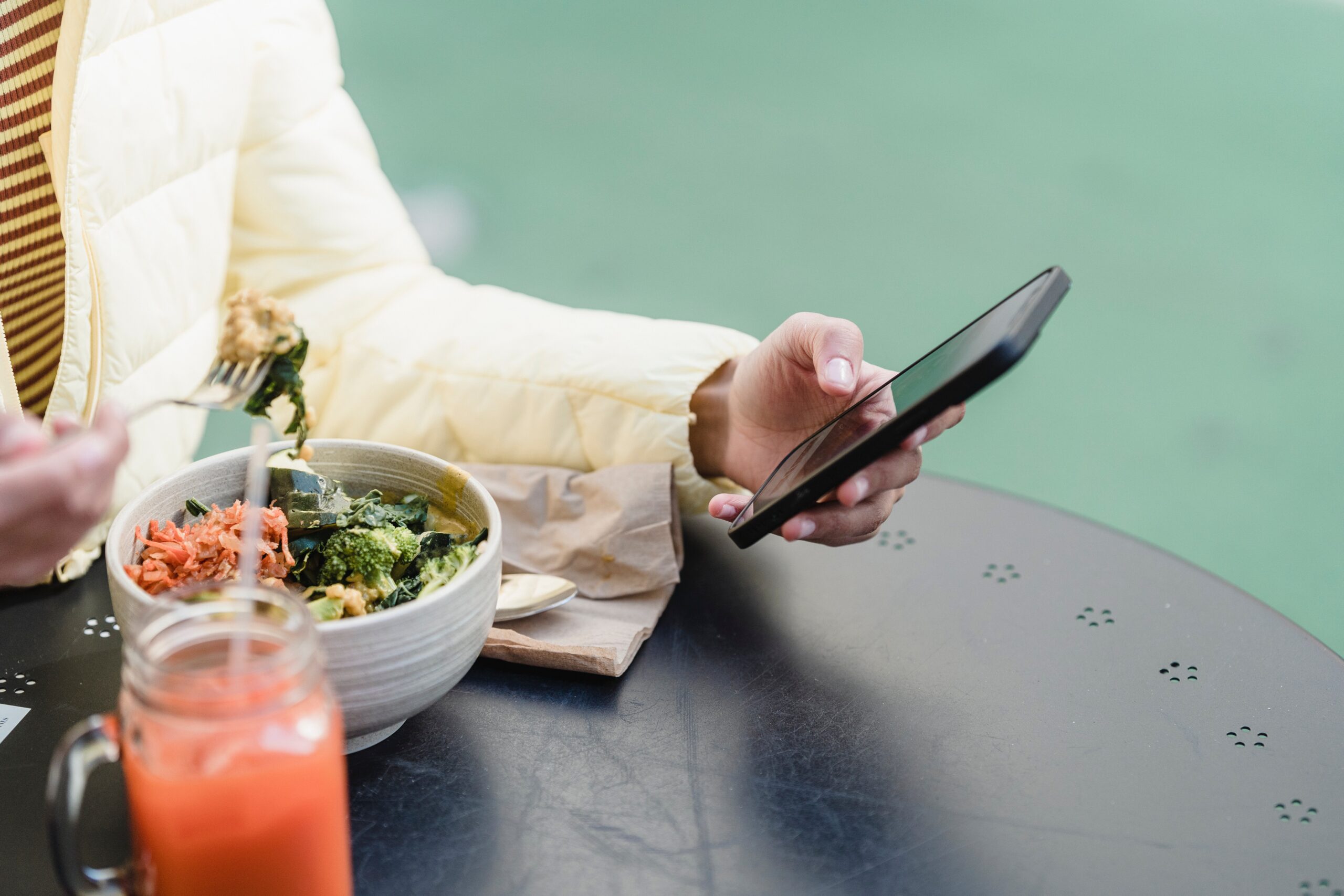 woman eating a healthy meal while looking at her cell phone
